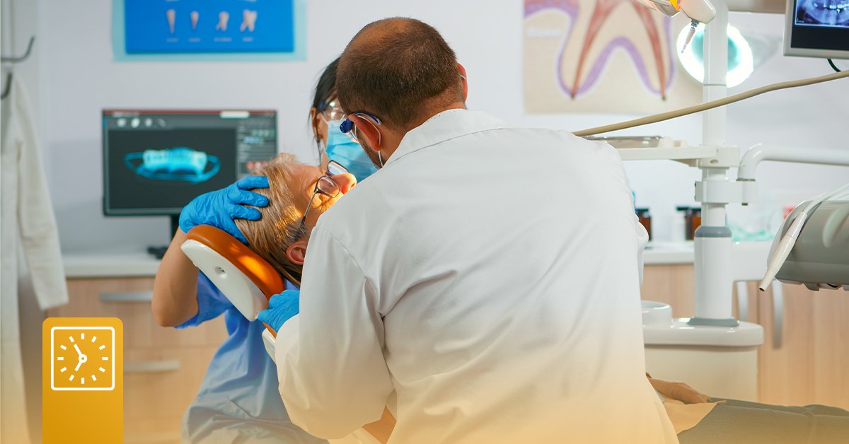 A dentist and dental assistant work on a patient in the chair of the dentist office