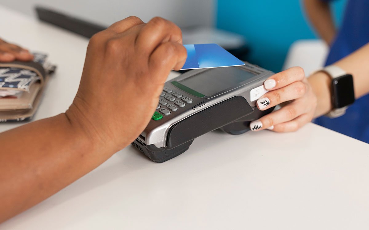 A dental patient taps their debit card on a card reader to pay for their dental services